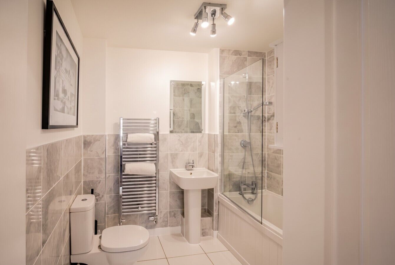 A modern bathroom with a toilet, sink, and glass shower enclosure.