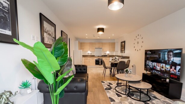 A modern living room with a large plant, a sofa, a coffee table, and a television. - 2-Bed Flat Sleeps 4 with Parking · Walk to Historic Dockyard Chatham (Gillingham)