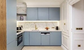 Eine Küche mit hellblauen Schränken, einer Marmor-Spritzschutzwand und einer weißen Arbeitsplatte.