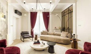Ein modernes Wohnzimmer mit einer Couch, Sesseln, einem Couchtisch und einer Deckenleuchte.