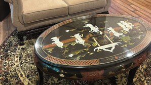 A living room with a beige sofa, a glass coffee table with floral designs, and a patterned rug.