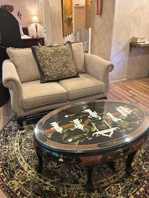 A living room with a beige sofa, a glass coffee table with floral designs, and a patterned rug.