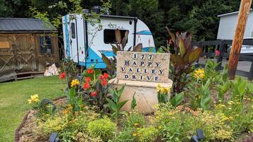Ein Gartenbereich mit einem Schild, auf dem '177 Happy Valley Drive' steht, umgeben von verschiedenen Pflanzen und Blumen.