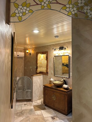 A bathroom with a wooden vanity, a mirror, and a decorative wall.