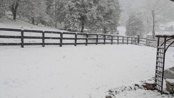 Schneebedeckte Landschaft mit Holzzaun und Metalltor.