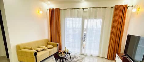 Una sala de estar con un sofá, un sillón verde, una mesa de centro y un mueble para televisor.
