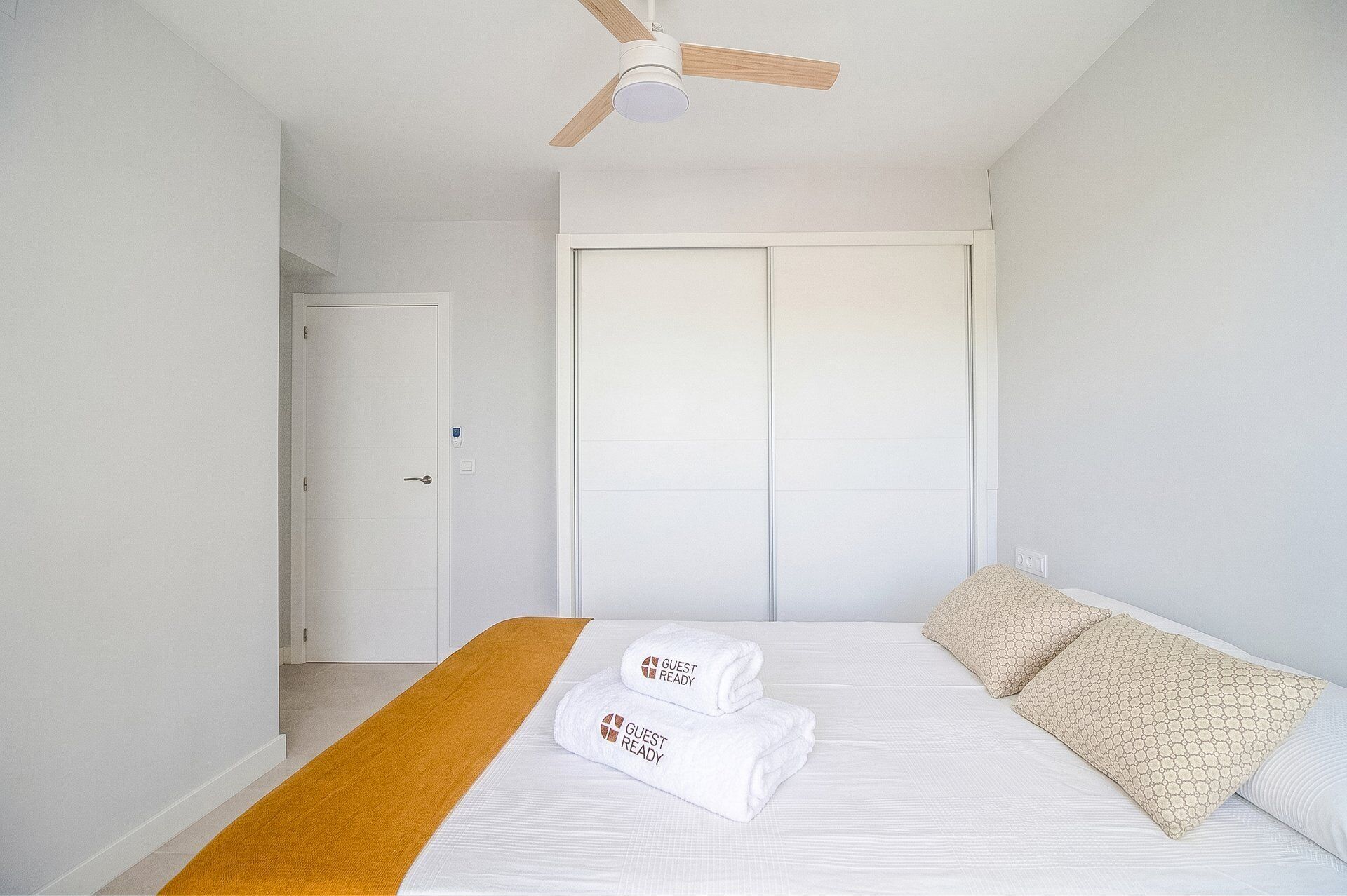 A hotel room with a bed, a ceiling fan, and a wardrobe.