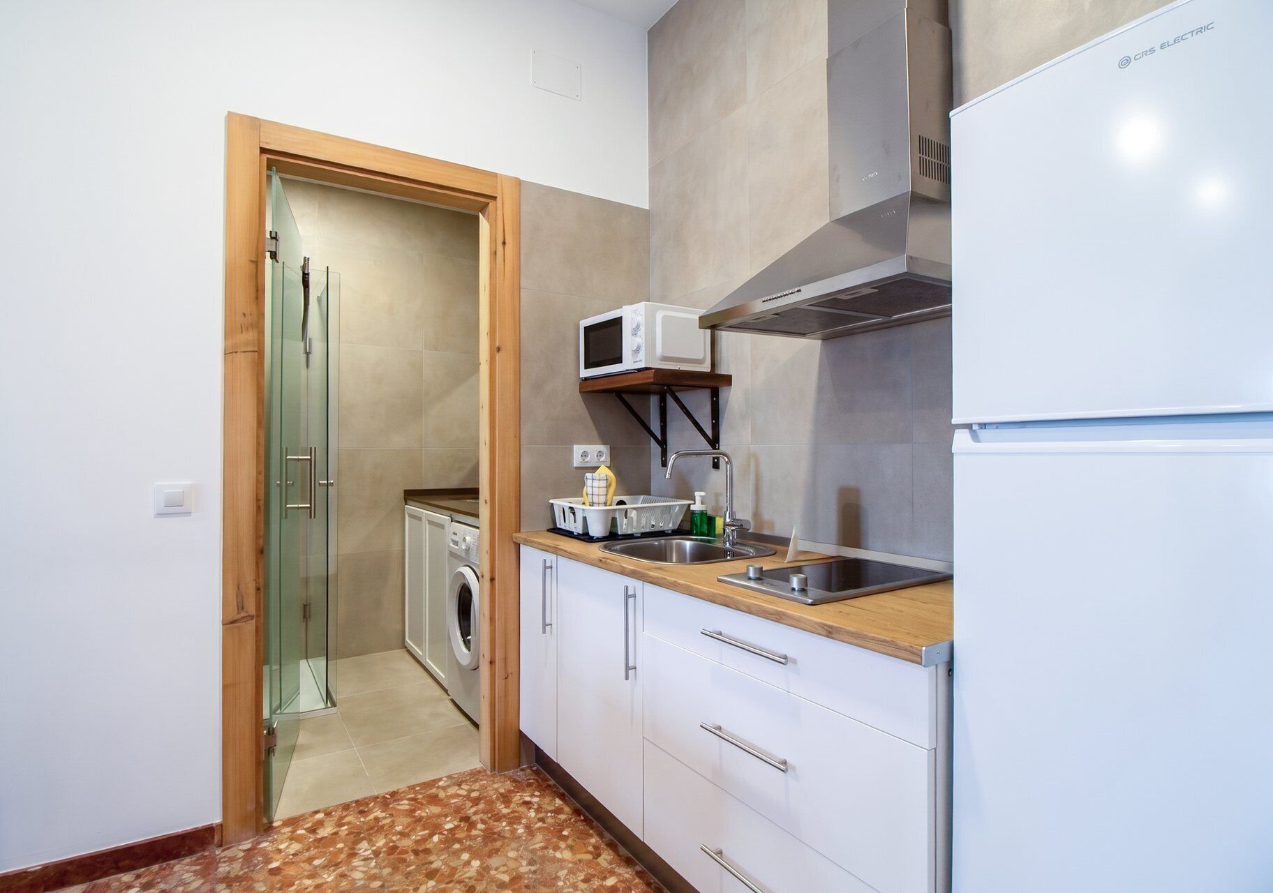 Una cocina compacta con lavadora, microondas y refrigerador.