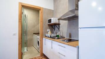 Una cocina compacta con lavadora, microondas y refrigerador.