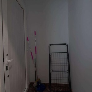 Une pièce avec une porte fermée, un étagère en métal et des outils de nettoyage.