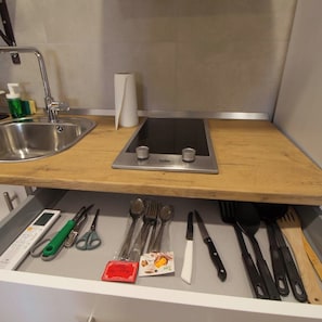 Une cuisine équipée d’un évier, d’une cuisinière et de divers ustensiles.