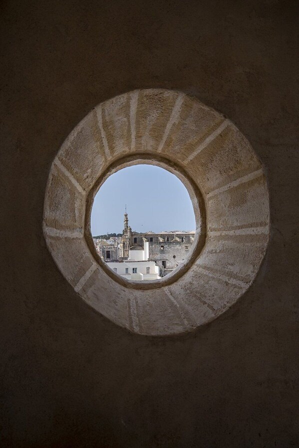 A circular window with a view of a cityscape, including a prominent tower. - GuestReady - La Cruz 1C (El Puerto de Santa María)