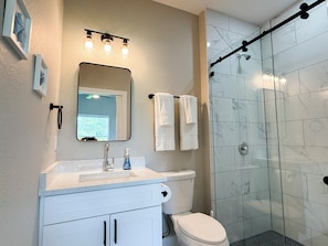 Un baño con inodoro, lavamanos, espejo y ducha.