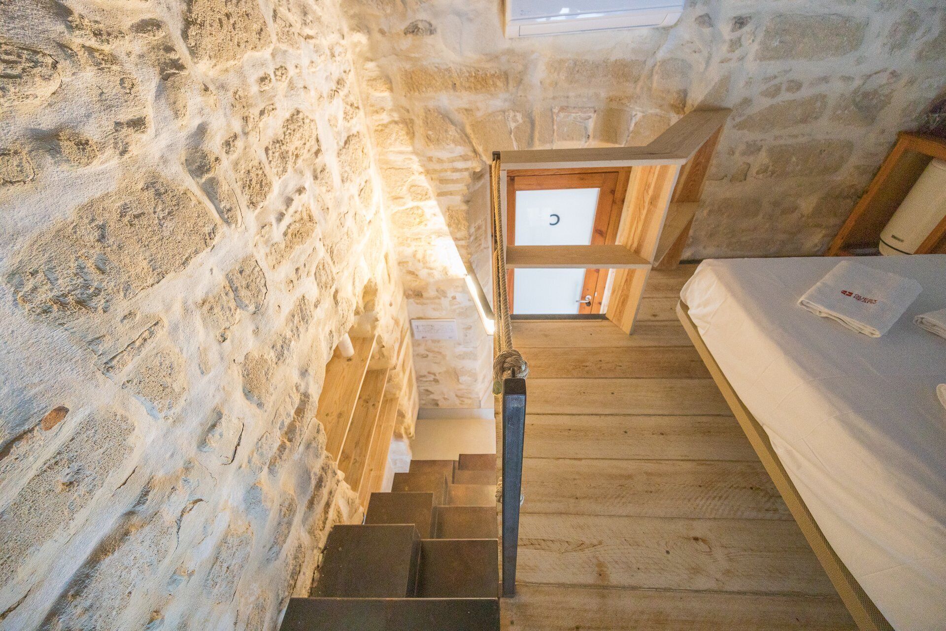Eine Holztreppe führt zu einem Bett mit einer weißen Matratze und einem Handtuch.