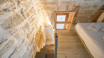 Eine Holztreppe führt zu einem Bett mit einer weißen Matratze und einem Handtuch.