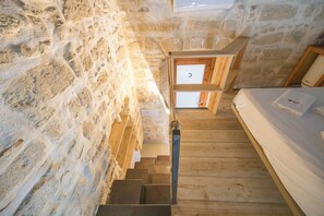 Eine Holztreppe führt zu einem Bett mit einer weißen Matratze und einem Handtuch.