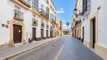 A cobblestone street lined with white buildings, some with balconies and windows.