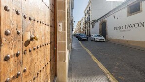 A street view with a wooden door and a building labeled 'Fino Pavon.' - GuestReady - La Cruz Bajo C (El Puerto de Santa María)