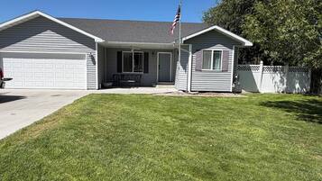 A residential property with a garage, a front porch with a bench, and a small shed.