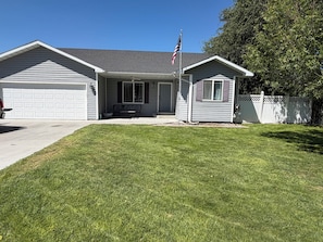 A residential property with a garage, a front porch with a bench, and a small shed. - Adventure Hub (Filer)