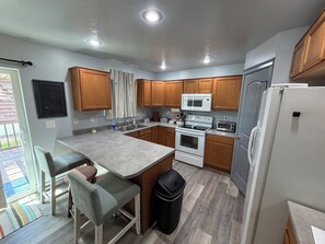 A compact kitchen with wooden cabinets, a built-in microwave, a stove, and a refrigerator.