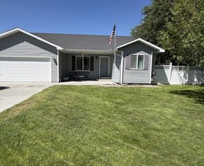 A single-story house with a garage, a front porch, and a small attached shed.