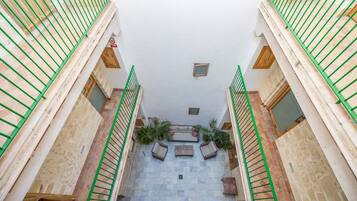 Un edificio de varios niveles con una escalera central, barandillas de madera y piso de baldosas.