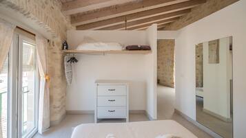 Un dormitorio con cama, cómoda, espejo y ventana con cortinas.