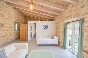 A room with a bed, a sofa, a glass-top table, and a view through a window. - GuestReady - La Cruz Ático (El Puerto de Santa María)