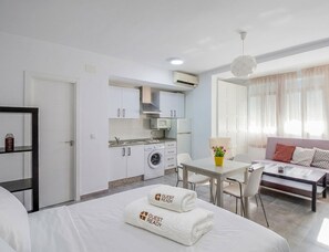Ein kompaktes Hotelzimmer mit Bett, einer kleinen Küchenzeile, einem Essbereich und einer Sitzecke.