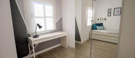Un dormitorio con cama, escritorio, espejo y ventilador de techo.