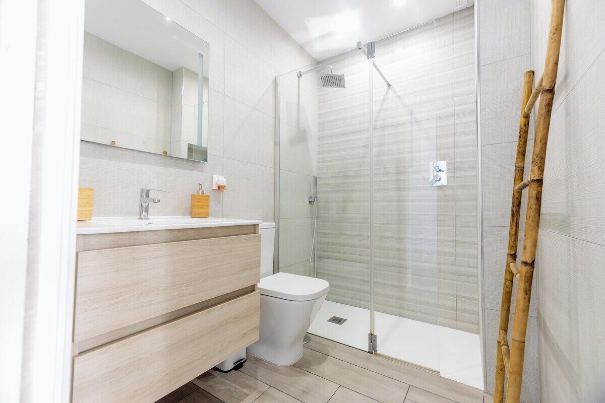 Une salle de bain moderne avec une douche à parois de verre, des toilettes blanches et un meuble-lavabo en bois.