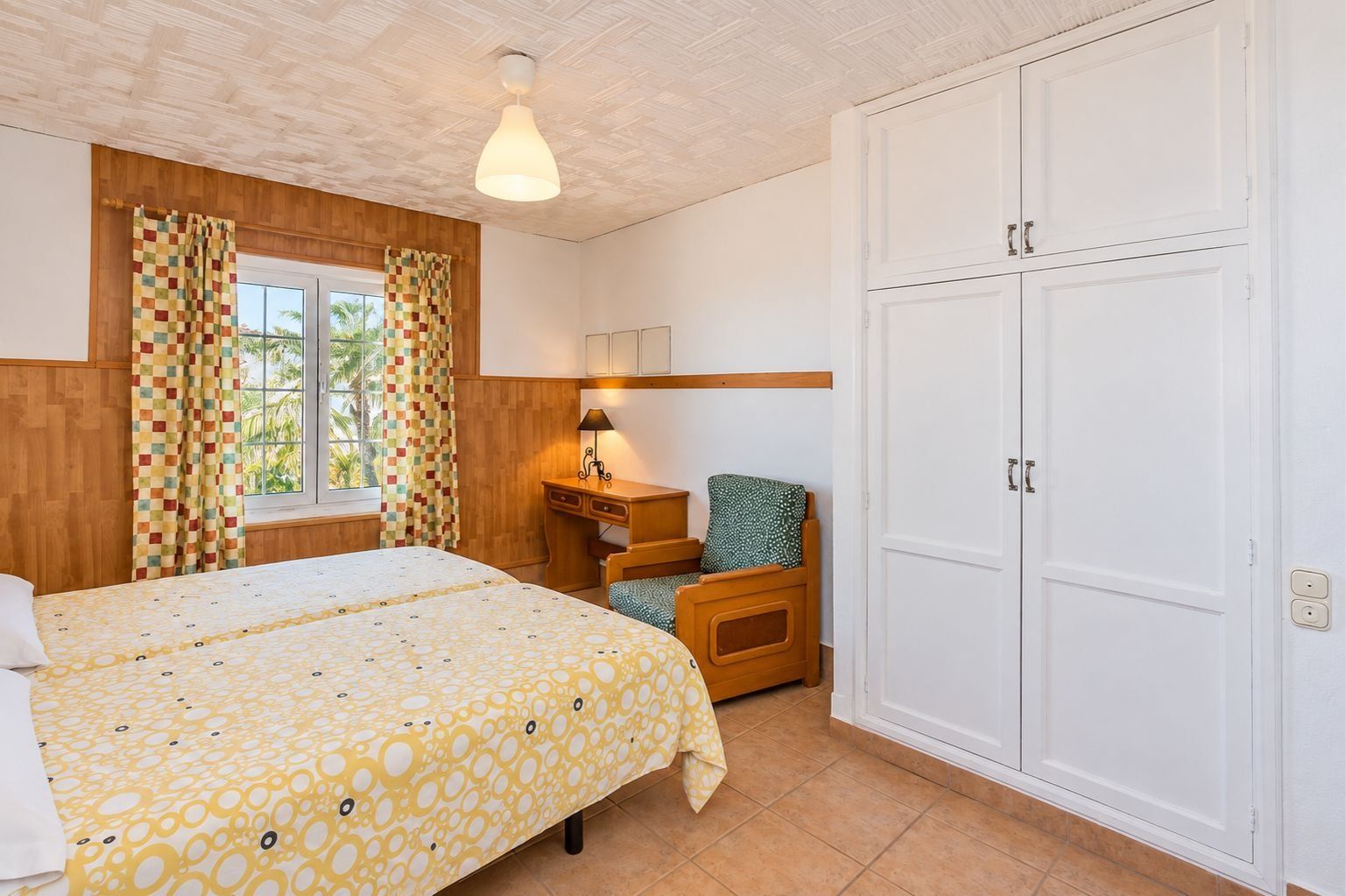 Ein Schlafzimmer mit Bett, Schreibtisch, Stuhl und Kleiderschrank.