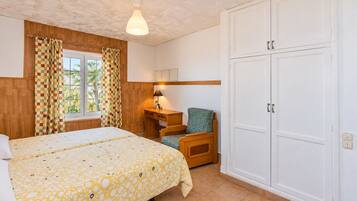 Ein Schlafzimmer mit Bett, Schreibtisch, Stuhl und Kleiderschrank.