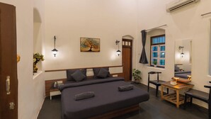 Un dormitorio con una cama grande, lámparas de noche, un cuadro, una ventana con cortinas y un equipo de aire acondicionado.
