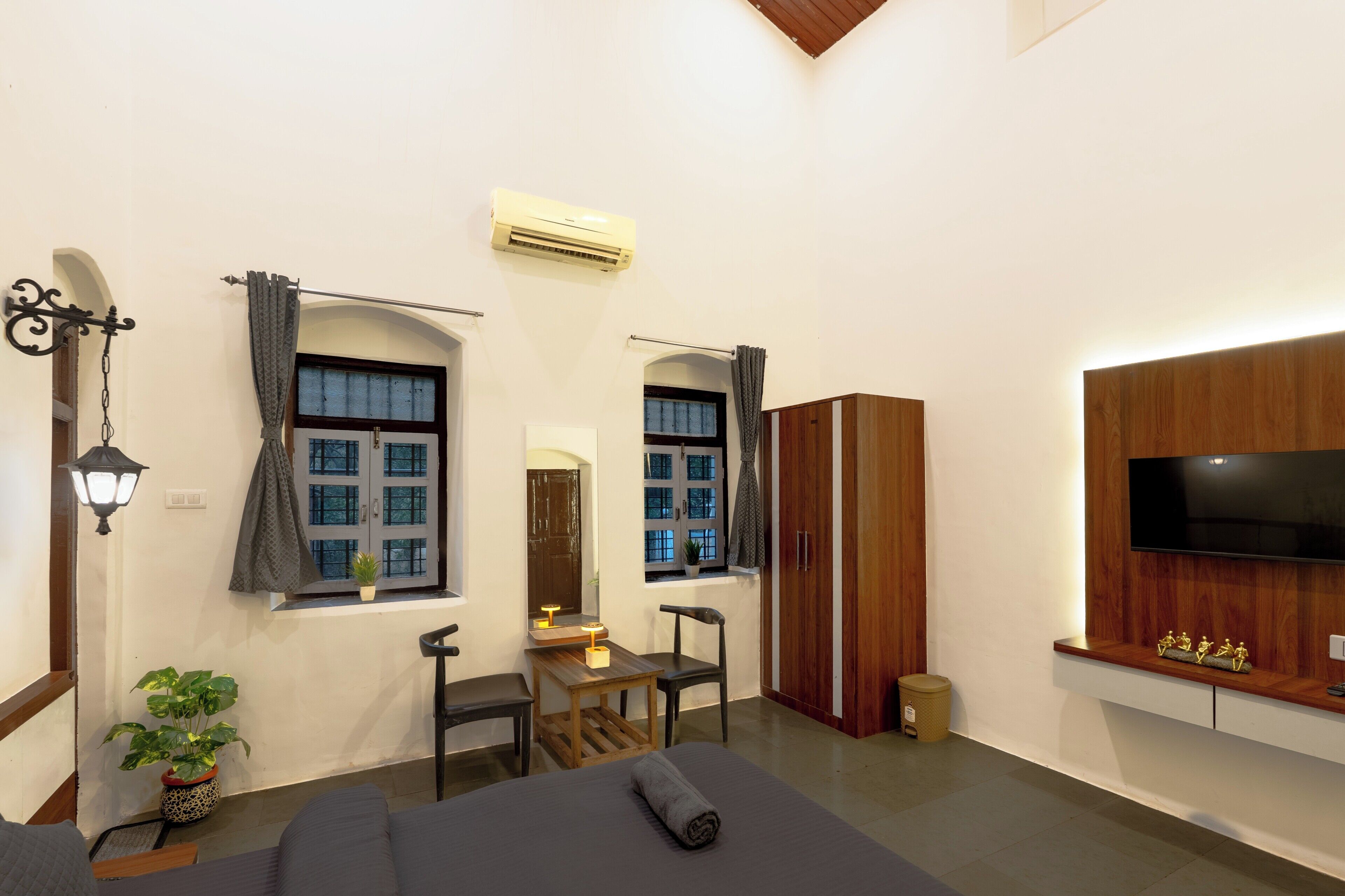 Habitación de hotel con cama, escritorio, dos sillas, televisor y armario.