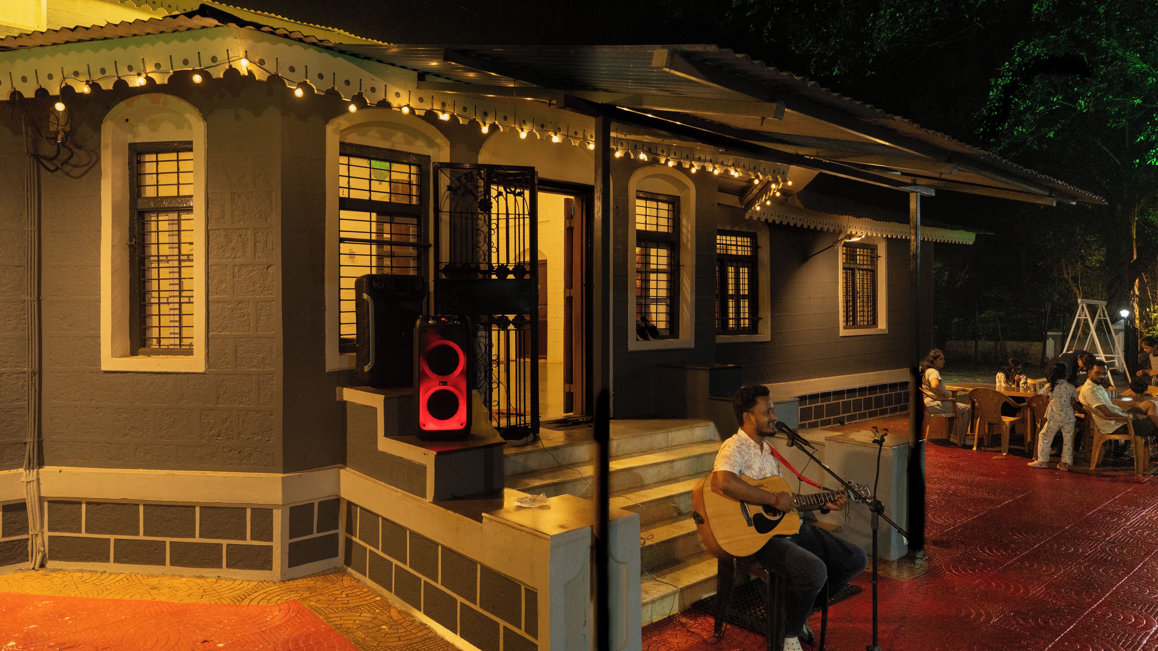 Un edificio con un porche, un guitarrista y un micrófono.