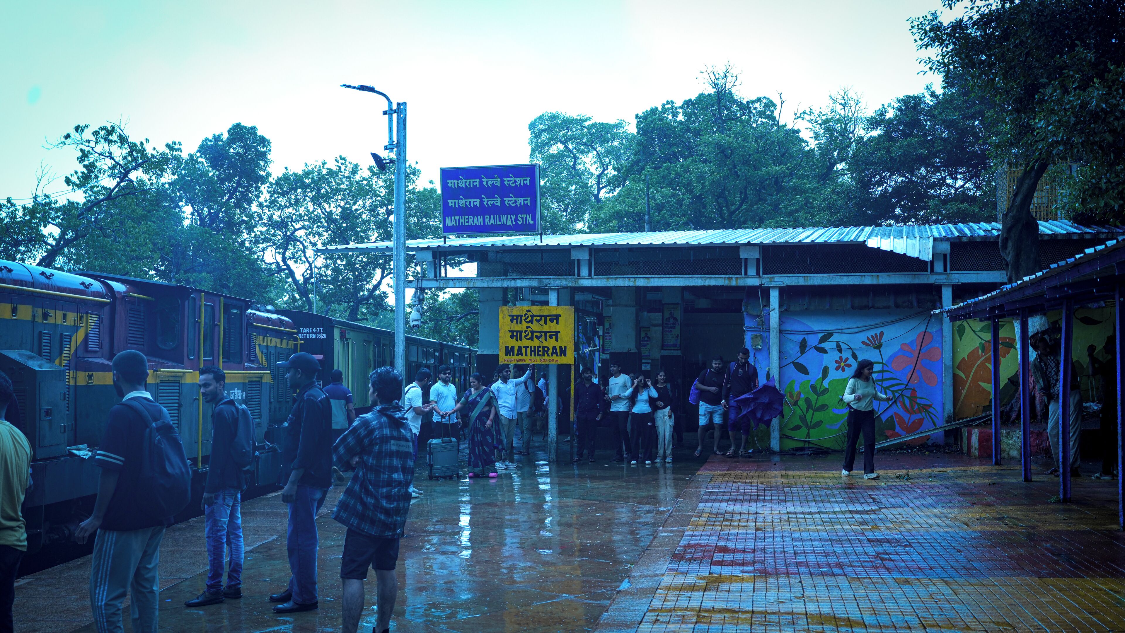 A train station platform with a yellow sign indicating the Matheran Railway Station.