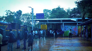 A train station platform with a yellow sign indicating the Matheran Railway Station.