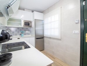 A modern kitchen with white cabinetry, a stainless steel refrigerator, a microwave, and a kettle. - GuestReady - Chiclana Labarrosa (Chiclana de la Frontera)