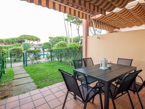 An outdoor patio with a table and chairs, a tiled floor, and a green lawn. - GuestReady - Chiclana Labarrosa (Chiclana de la Frontera)
