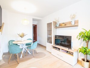 A modern living room with a television, a dining table with chairs, and a potted plant. - GuestReady - Chiclana Labarrosa (Chiclana de la Frontera)
