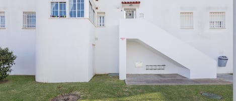 Un bâtiment blanc doté de nombreuses fenêtres et d’un petit balcon. Un escalier mène à un étage supérieur.