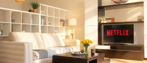 A modern living room with a sofa, coffee table, TV, bookshelf, and decorative items.