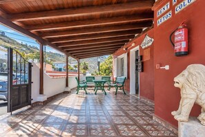 Un espacio al aire libre techado con una mesa, sillas, un extintor y una estatua de león.