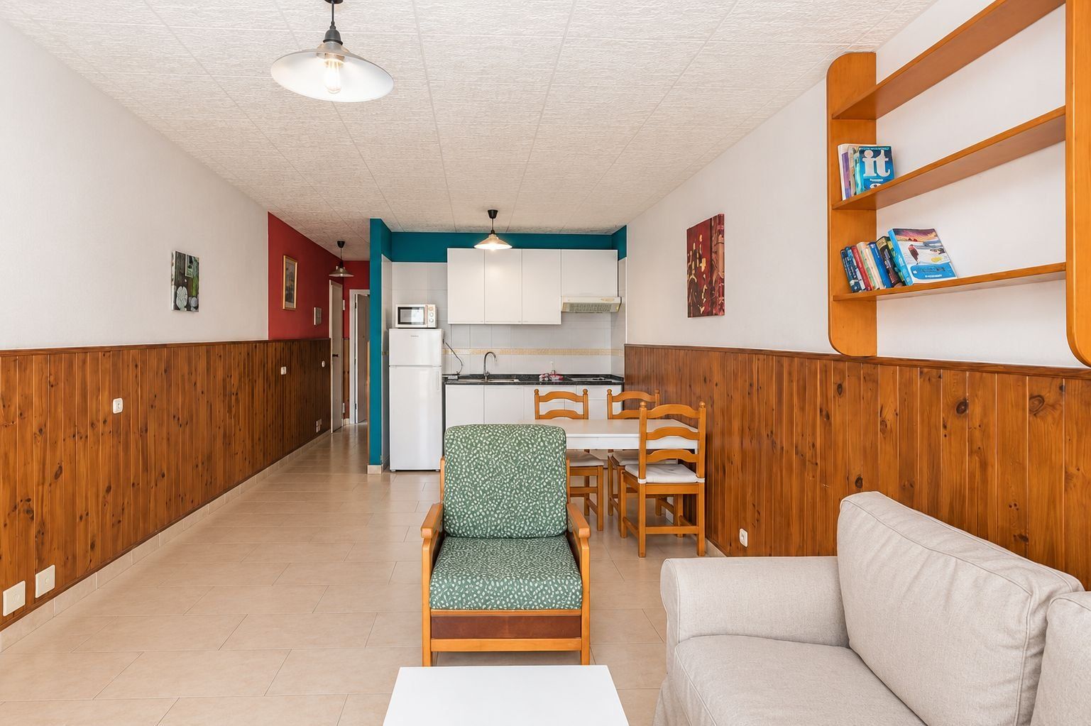 Un espacio habitable compacto con kitchenette, comedor y zona de estar.