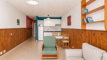 Un espacio habitable compacto con kitchenette, comedor y zona de estar.