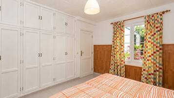 Un dormitorio con cama, armario y ventana con cortinas.