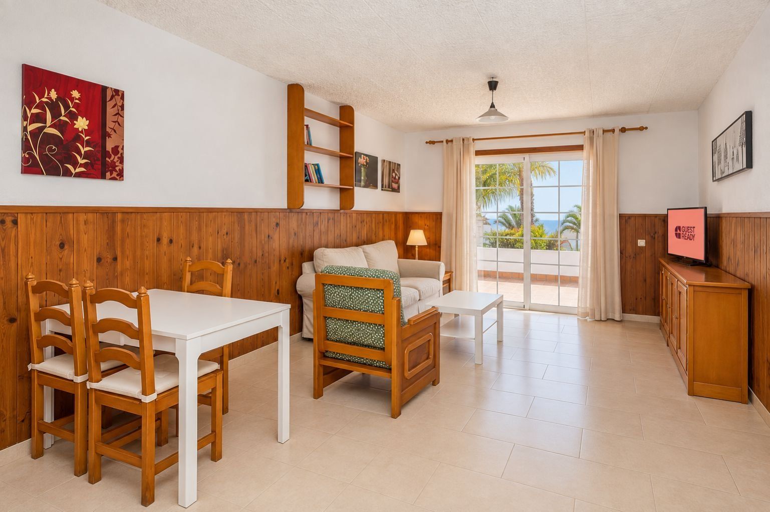 Una habitación con mesa de comedor, sillas, sofá, televisión y un balcón con vistas.