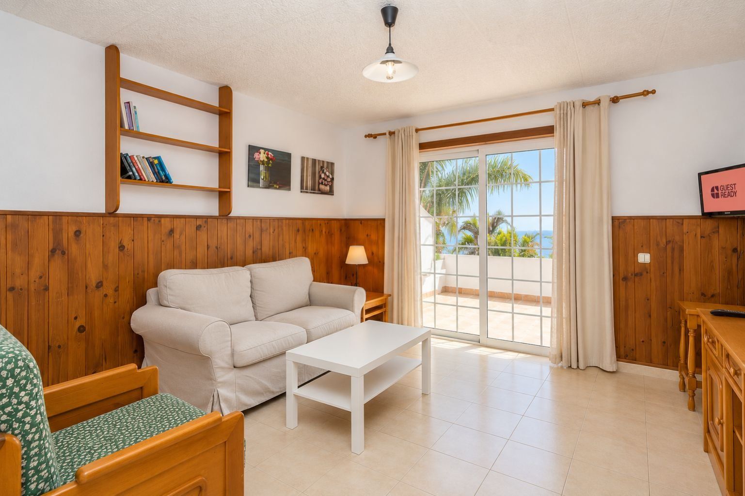 Una sala de estar amoblada con un sofá, una mesa de centro, un televisor y vistas al exterior.